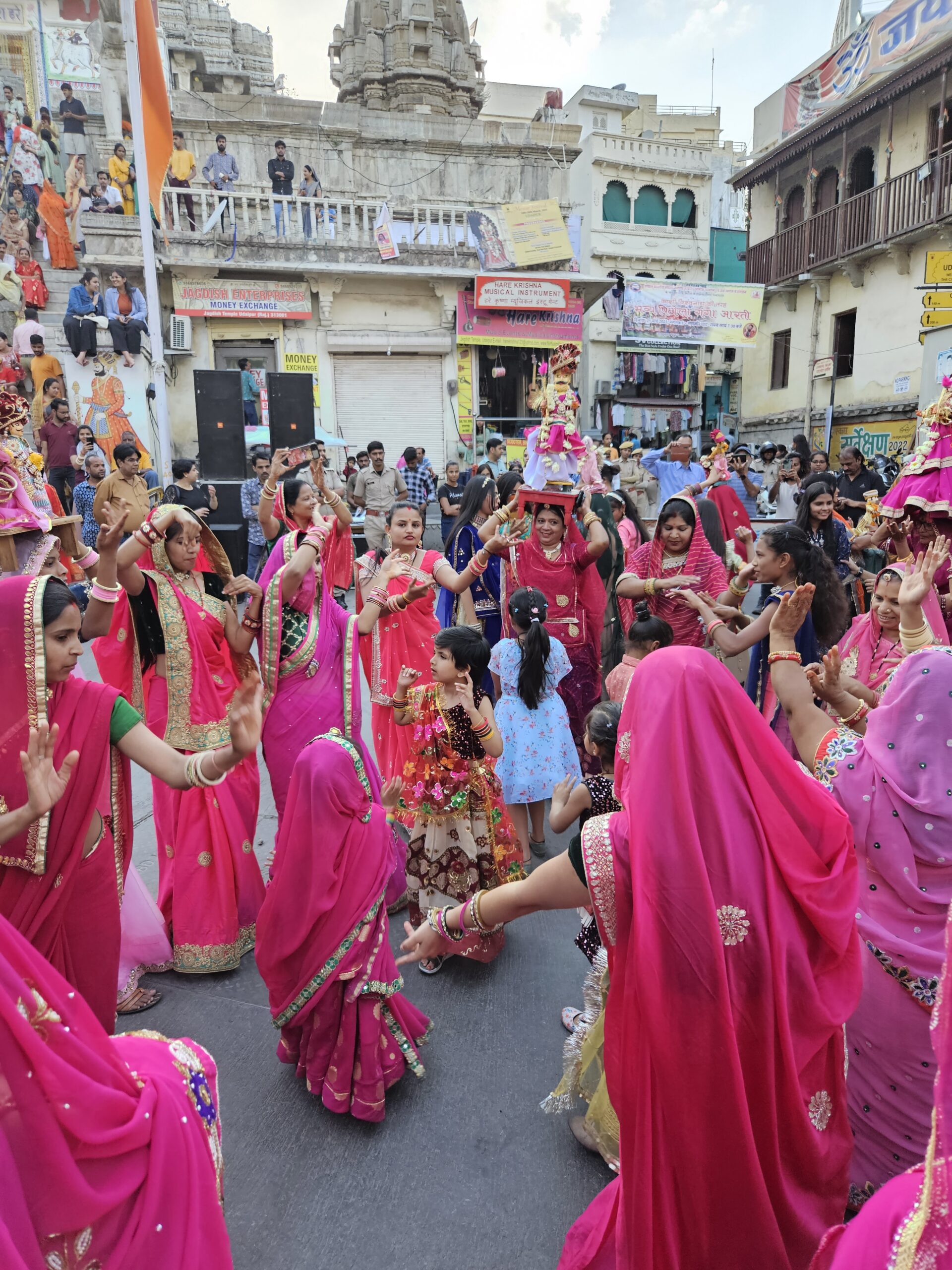 Traditionele dans in de straten van Udaipur met vrouwen en kinderen in felroze sari's tijdens een religieus festival.