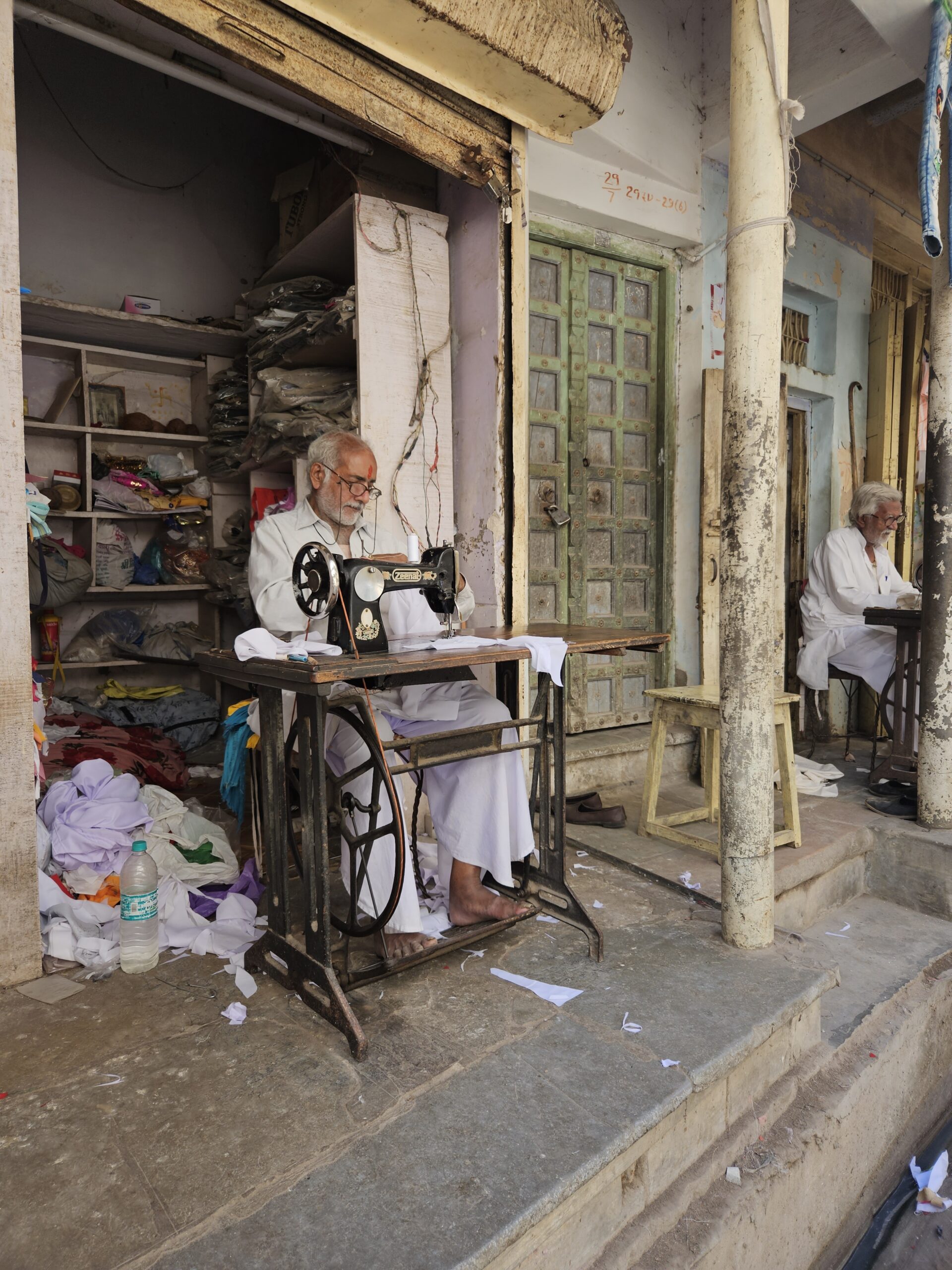 Kleermaker in India werkt op een traditionele naaimachine voor zijn winkel.