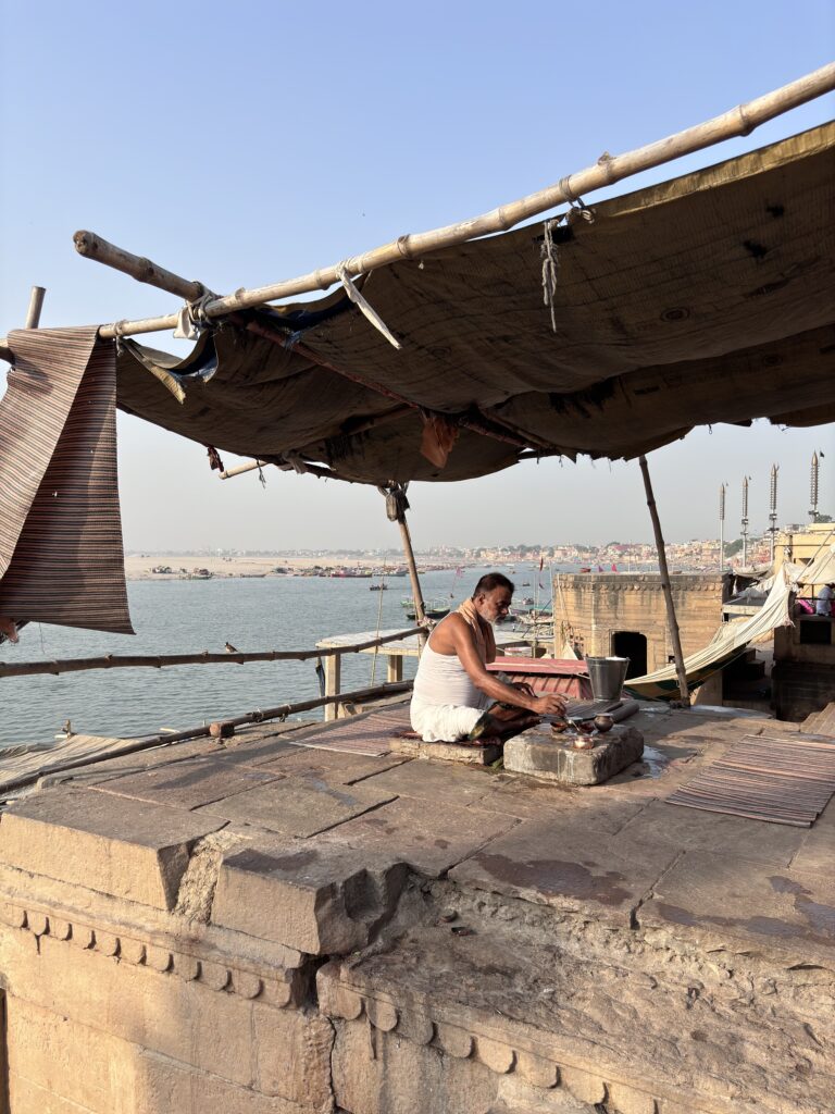 Man in traditionele kleding verricht ritueel op de ghats van Varanasi aan de rivier de Ganges, India.