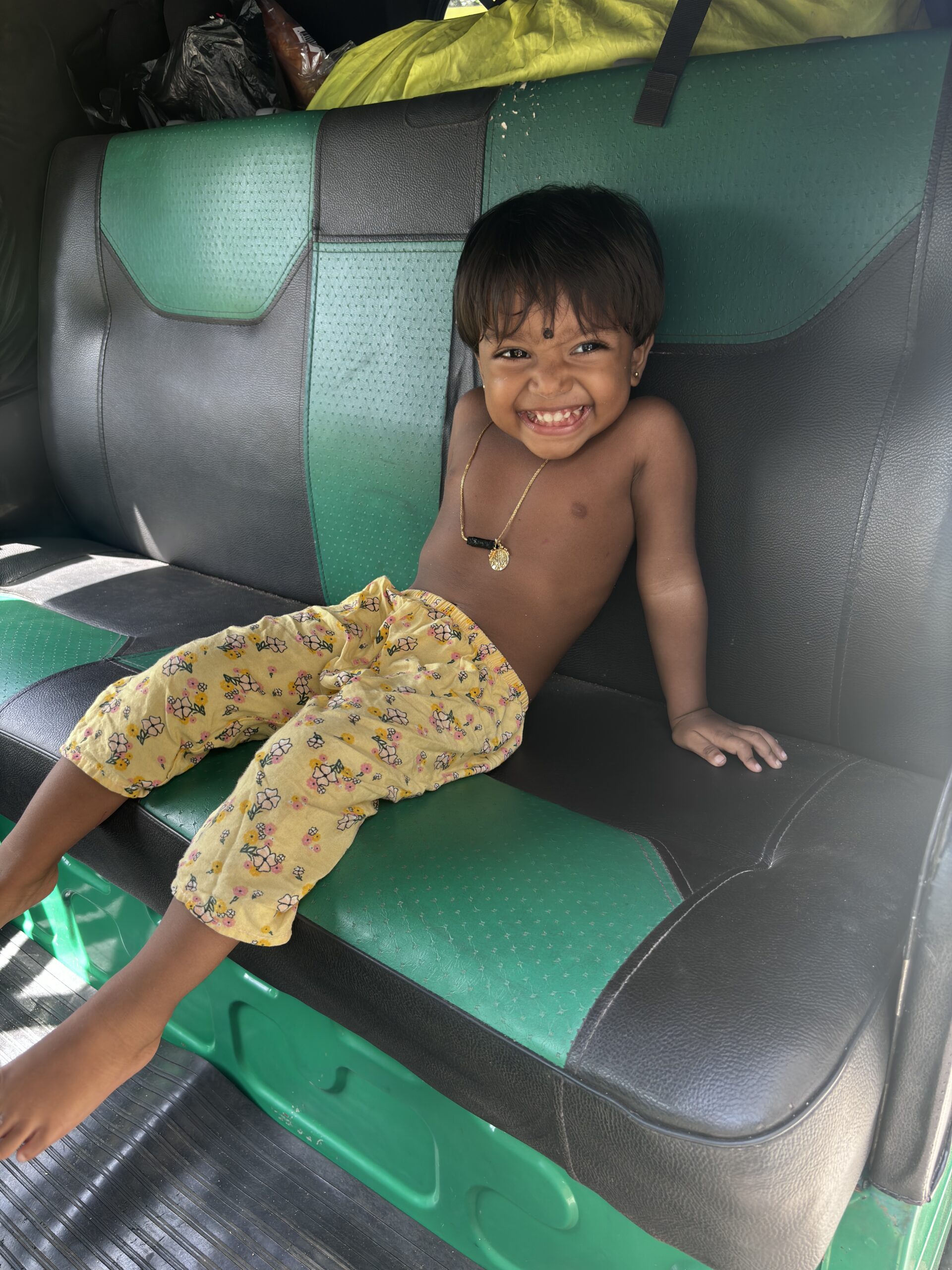 Lachend kind zit op de achterbank van een tuktuk in Sri Lanka.